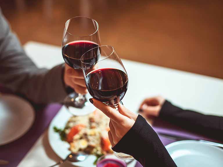 couple cheering with wine glasses at table
